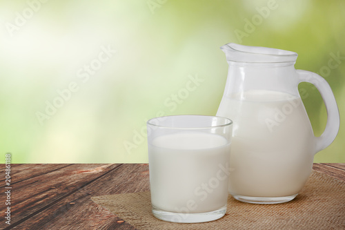 Jug of milk and glass milk on linen napkin on wooden table