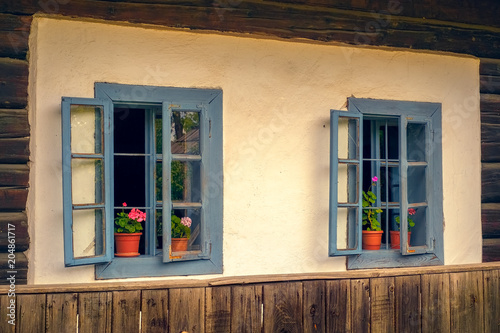 Romanian traditional wooden house with old blue windows and flowers photo