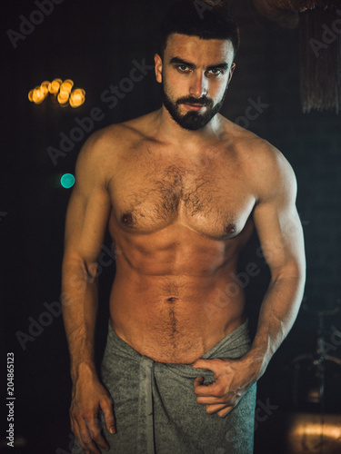 Foto A handsome, muscular man with a beard lies in a bronze bathroom