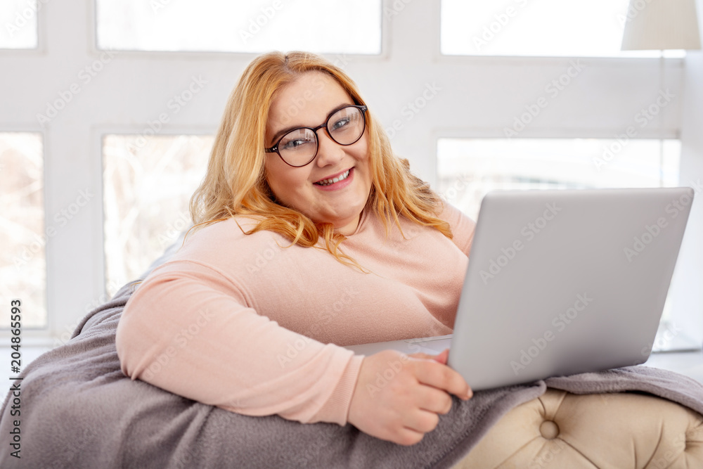 I am happy. Exuberant plump woman smiling while working on her laptop I am happy. Exuberant plump woman smiling while working on her laptop