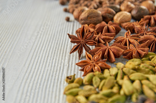 Aromatic Indian spices on the gray kitchen table: star anise, nutmeg, cardamom close up. Spices texture background with free copy space. Ingredients for spicy food. Side view