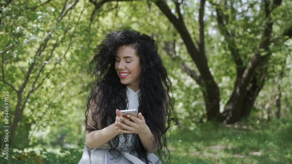 Pretty brunette greet with someone in garden when she's using her phone Pretty brunette greet with someone in garden when she's using her phone