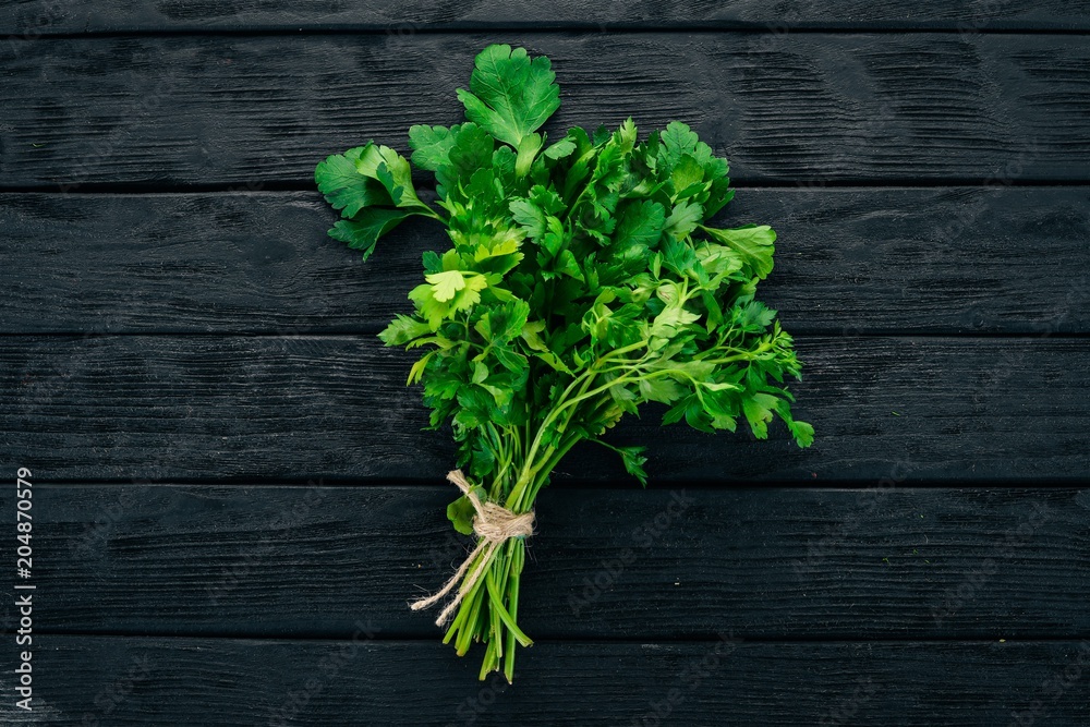 Fresh parsley. On a black wooden background. Healthy food. Top view. Copy space. Fresh parsley. On a black wooden background. Healthy food. Top view. Copy space.