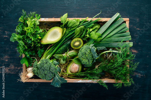 Fototapeta Naklejka Na Ścianę i Meble -  Fresh green vegetables and fruits in a wooden basket. Healthy food. Top view. Copy space.