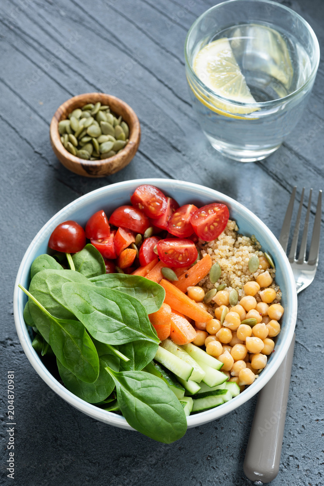 Chickpea salad bowl on concrete background. Healthy buddha bowl with baby spinach, baby carrots, chickpeas, quinoa and tomatoes