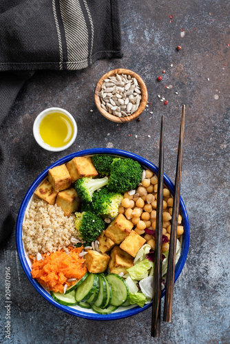 Buddha Bowl with quinoa, tofu, broccoli, sweet potato and cucumber. Nourishing buddha bowl. Healthy vegan or vegetarian salad bowl, table top view