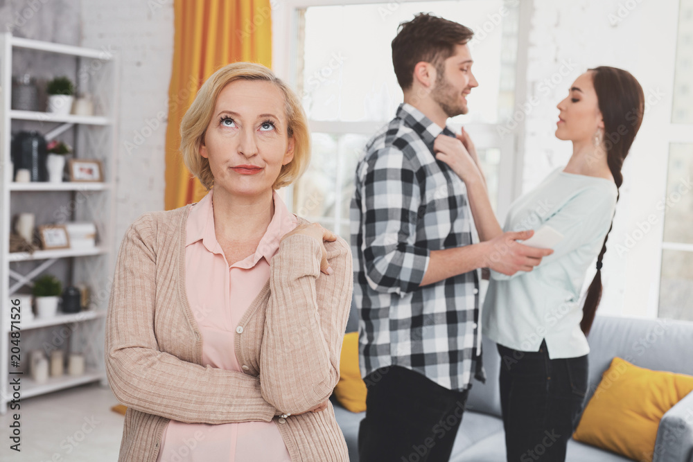 Bad mood. Unhappy aged woman standing in the living room while thinking about her daughters husband Bad mood. Unhappy aged woman standing in the living room while thinking about her daughters husband
