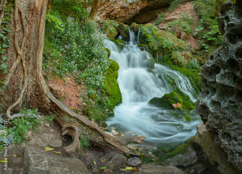 streams of clean water, Isichenko waterfall in Mezmay, Adygea, Caucasus surrounded by young green grass in the spring photo