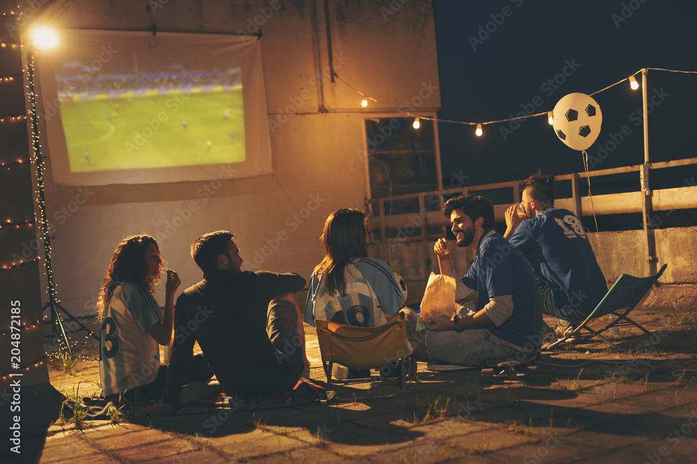 Group of friends watching football on a building rooftop