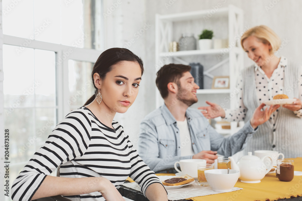 Family breakfast. Unhappy pretty woman looking at you while sitting at the breakfast table Family breakfast. Unhappy pretty woman looking at you while sitting at the breakfast table