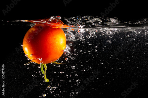 Red tomato in water on a black background
