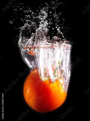 Red tomato in water on a black background