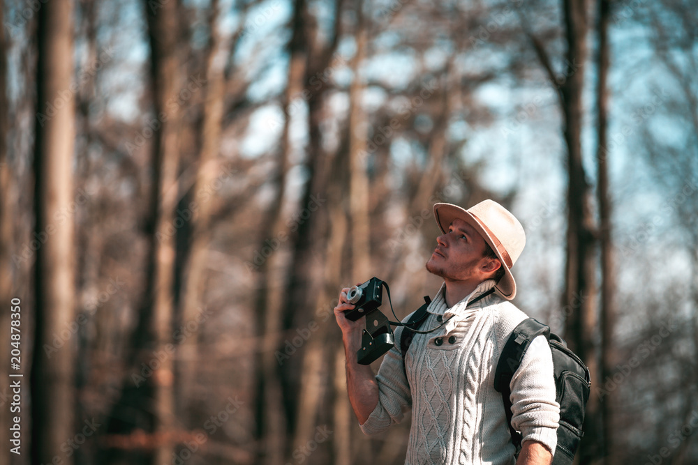 Traveler man with vintage camera and backpack, hipster tourist in forest