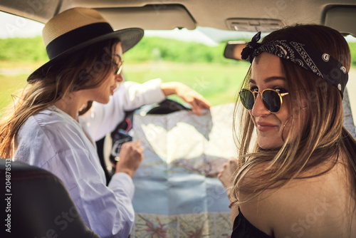 Two young women having fun on road trip,checking map. © chika_milan