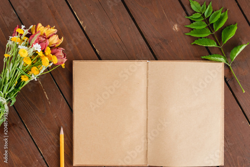 flat lay notepad-kraft, bouquet of flowers on a wooden backgrounddiary on a wooden background, top view.