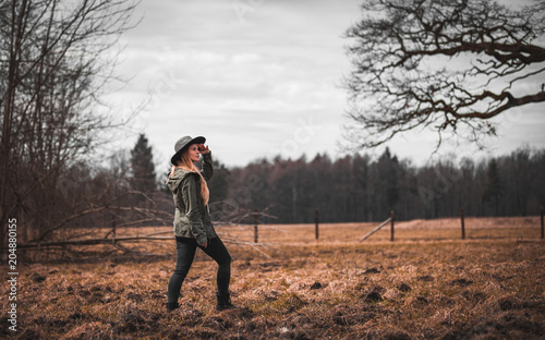 Rural scene with woman in hat walking on field, melancholic autumn mood