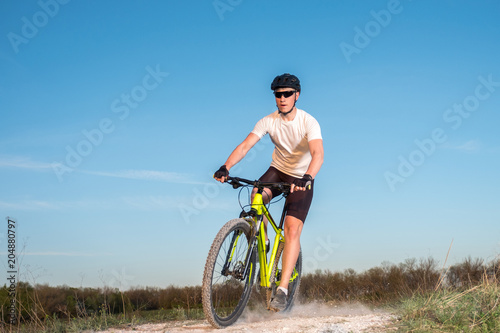 A cyclist in a white T-shirt rides a bike along the mountain path. The concept of extreme sports. Mountain bike.