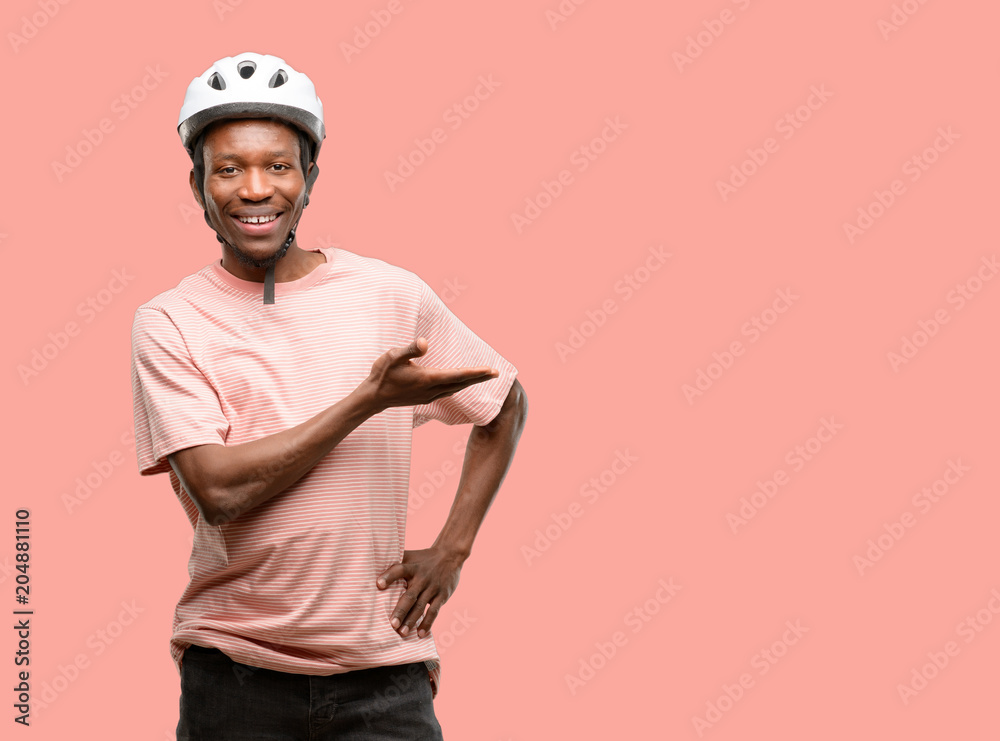 Black man wearing bike helmet holding something in empty hand
