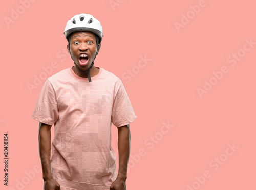 Black man wearing bike helmet stressful, terrified in panic, shouting exasperated and frustrated. Unpleasant gesture. Annoying work drives me crazy