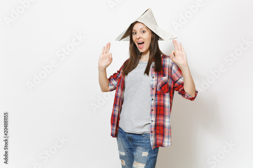 Young overjoyed beautiful woman in newspaper hat showing OK gesture isolated on white background. Accessories for renovation apartment room. Repair home concept. Copy space for advertisement.