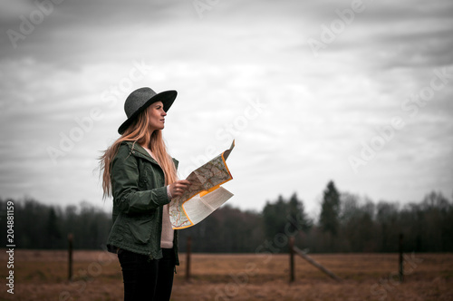 Rural scene with traveler woman in hat with map, melancholic autumn mood