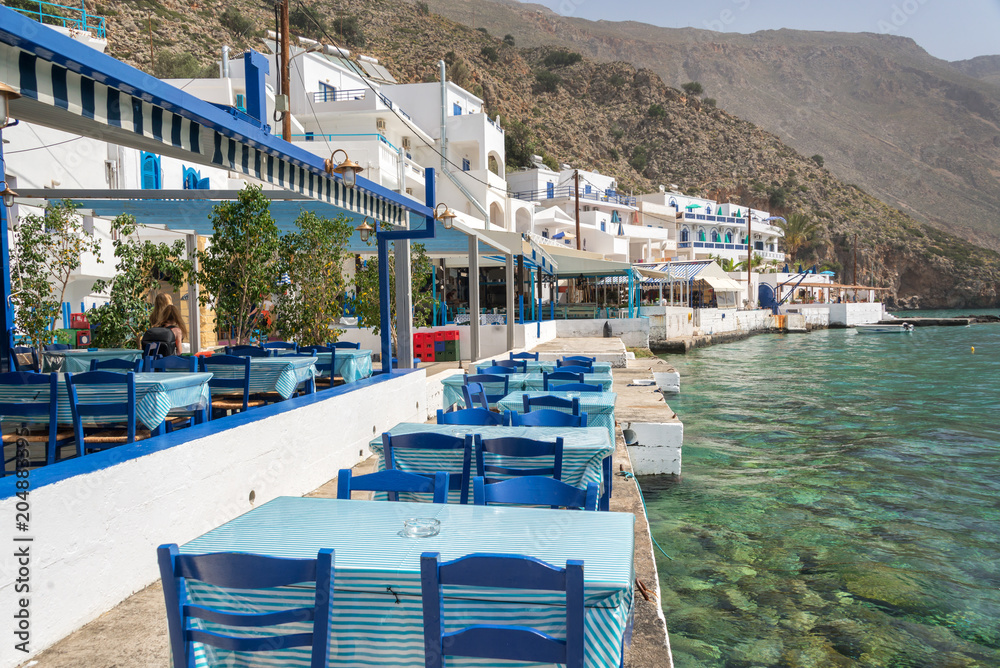 Restaurant tables by the sea in the scenic village of Loutro  in Crete, Greece