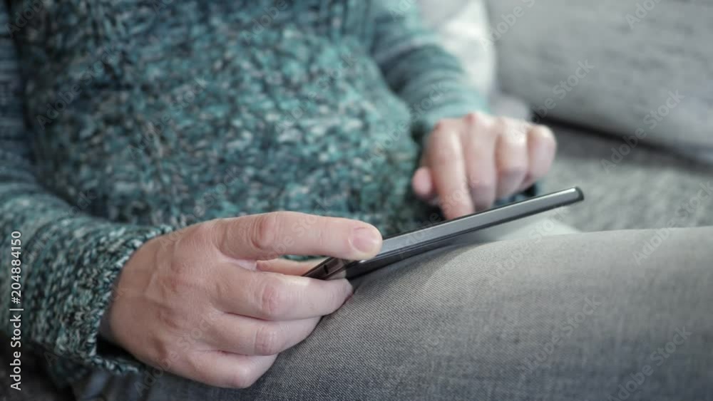 Woman touching smartphone on sofa Woman touching smartphone on sofa