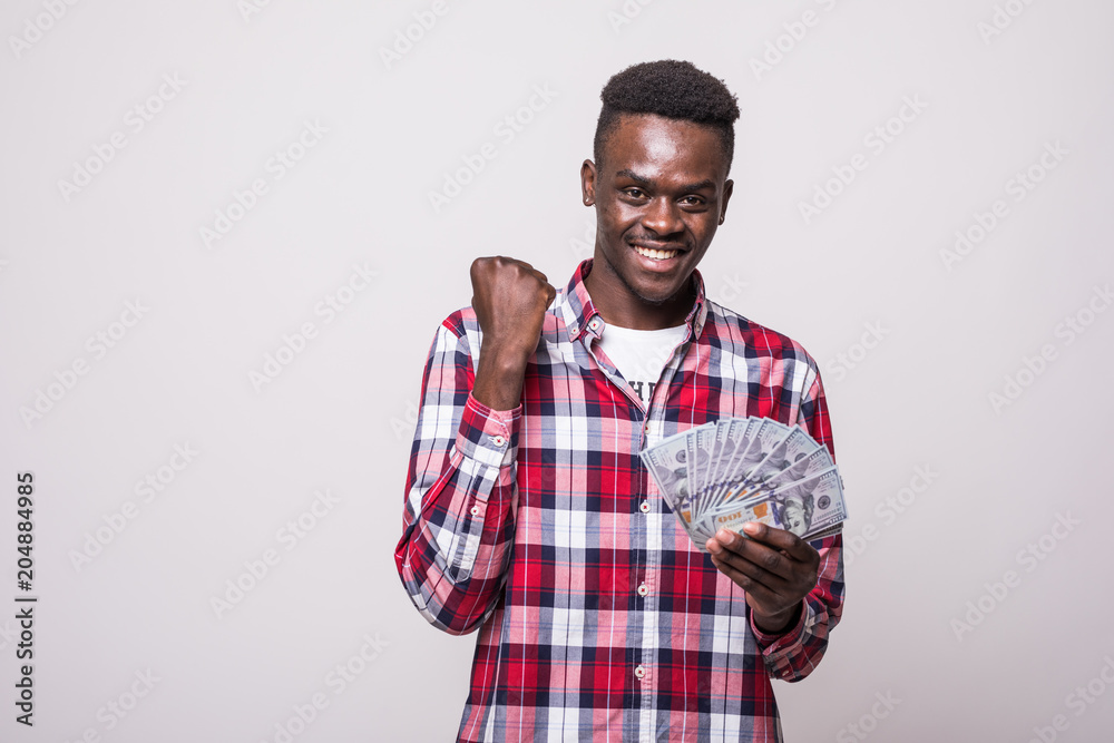 Portrait of a happy excited african man holding bunch of money banknotes and looking at camera isolated over white background Portrait of a happy excited african man holding bunch of money banknotes and looking at camera isolated over white background