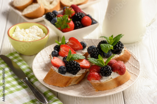 Healthy breakfast fruits and ricotta sandwiches- with strawberries, blueberries and blackberries.