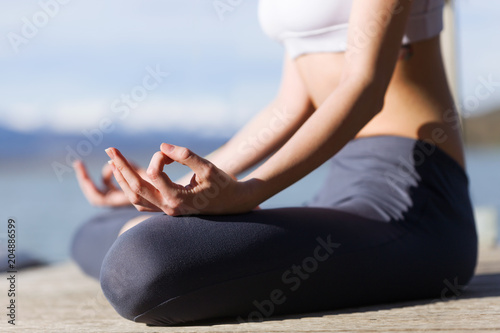 Close-up of young woman doing yoga next to the lake.