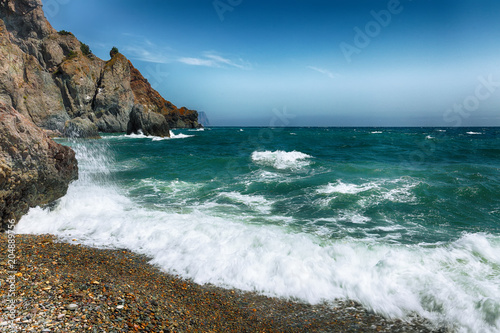 Sea waves crashing on the shore and flowing above seashore pebbles