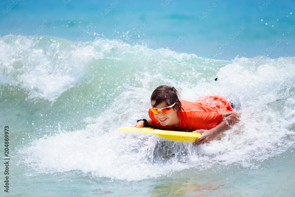 Child surfing on tropical beach. Surfer in ocean. Child surfing on tropical beach. Surfer in ocean.