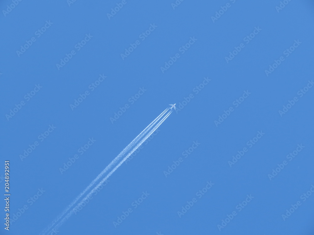 Jet airplane with contrail. Trace of the high flying plane in the blue sky Jet airplane with contrail. Trace of the high flying plane in the blue sky
