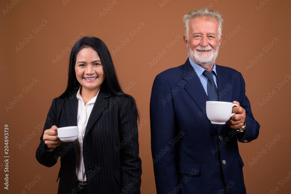 Mature multi-ethnic business couple against brown background Mature multi-ethnic business couple against brown background