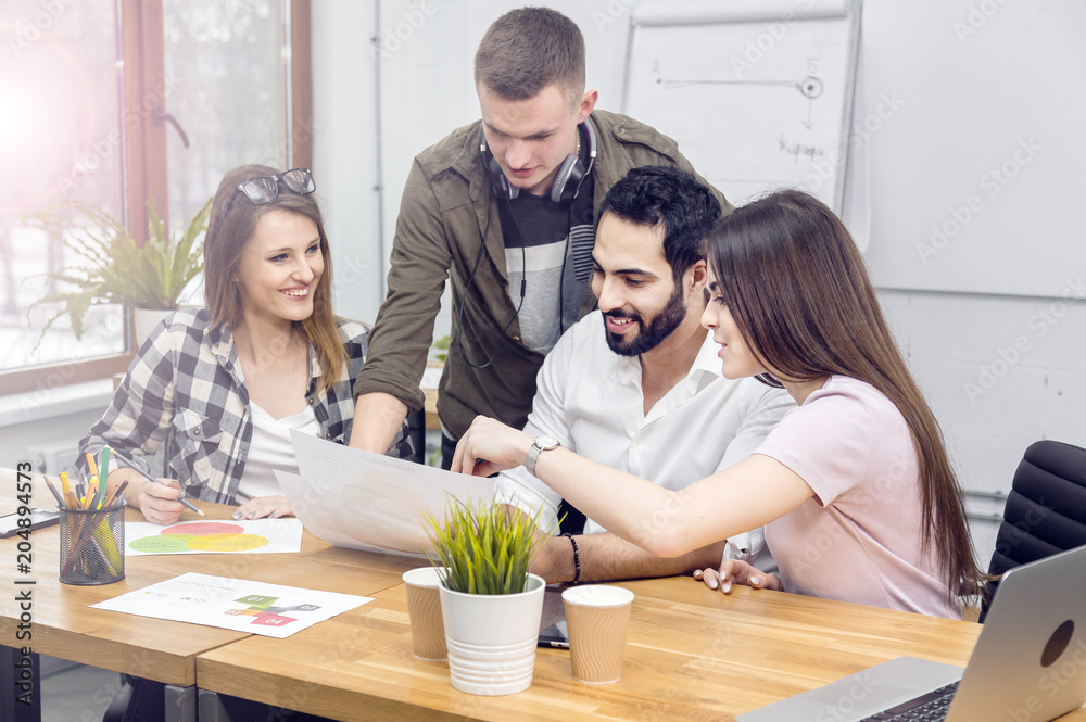 Team of office workers discussing diagrams sitting on working table ...