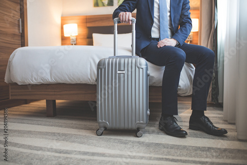 Young businessman with a suitcase in room