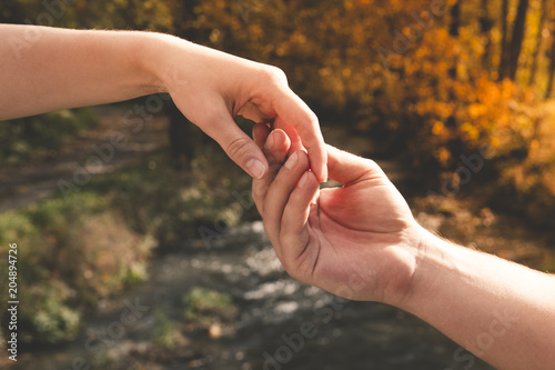 Mans hand gently holding the female against the background of the stream, concept of love and Valentine day © Bogdan