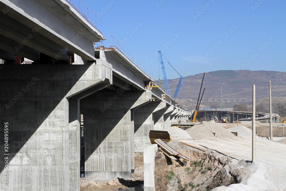 New highway under construction. A new bridge freeway made of concrete and metal to pass traffic from big city. An unfinished interstate bridge. Road under construction. Overpass road on a sunlight. New highway under construction. A new bridge freeway made of concrete and metal to pass traffic from big city. An unfinished interstate bridge. Road under construction. Overpass road on a sunlight.