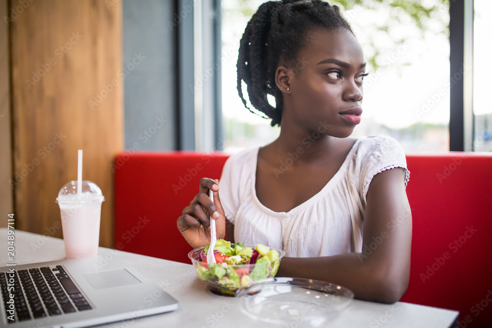 Beautiful woman have lanch eat salad at dinner sitting at cafe. Young african american woman sitting in a coffee shop and working on laptop. Beautiful woman have lanch eat salad at dinner sitting at cafe. Young african american woman sitting in a coffee shop and working on laptop.