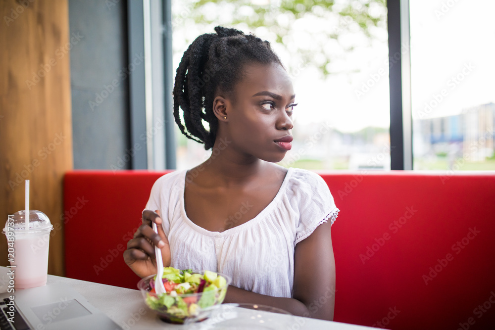 Young beautiful Afro-American woman using laptop and have dinner lanch in cafe