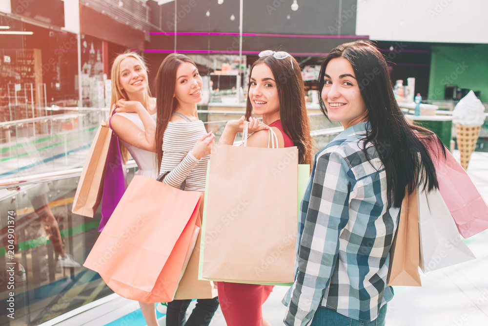 Girls are standing and posing. They are looking backwards and smiling. They are holding bags on their shoulders. Girls are standing and posing. They are looking backwards and smiling. They are holding bags on their shoulders.