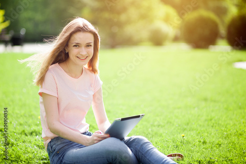 Girl with a sign sitting on the lawn and smiling. Copy space.