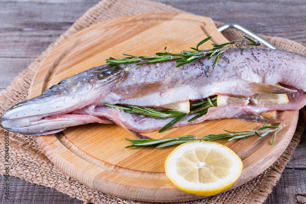 Fresh fish with lemon, lime, rosemary, salt and pepper on wooden board Fresh fish with lemon, lime, rosemary, salt and pepper on wooden board