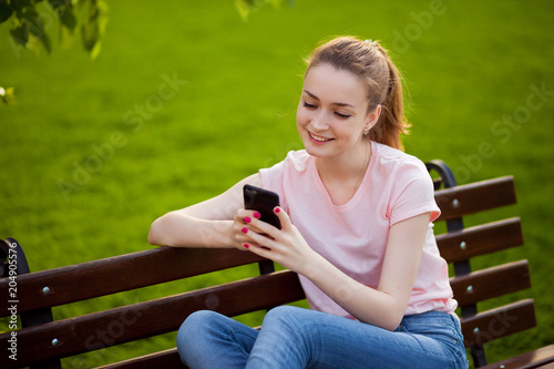 girl is texting on the phone while sitting in the Park
