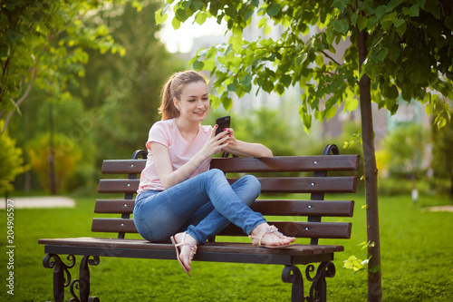 girl is texting on the phone while sitting in the Park