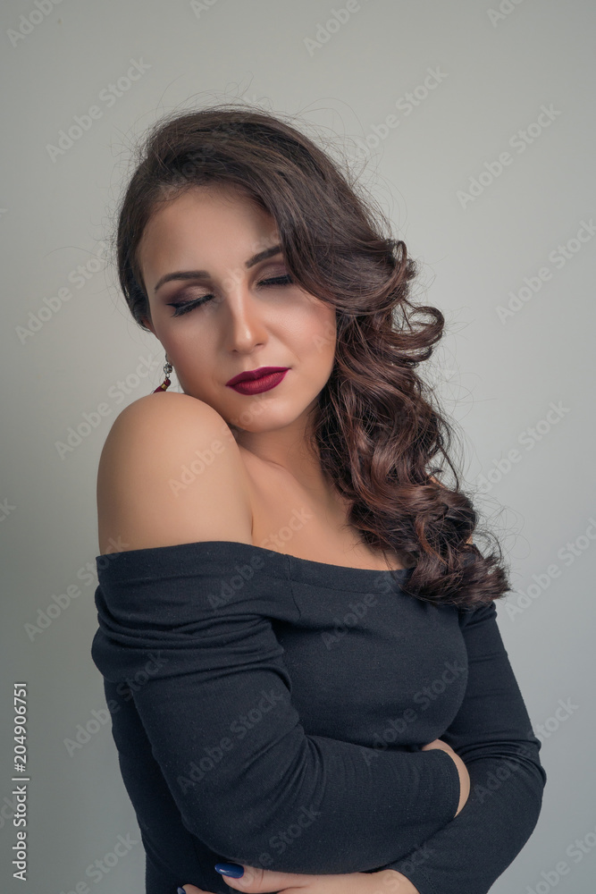 Portrait of a charming brunette with beautiful curly hair in a black dress Portrait of a charming brunette with beautiful curly hair in a black dress