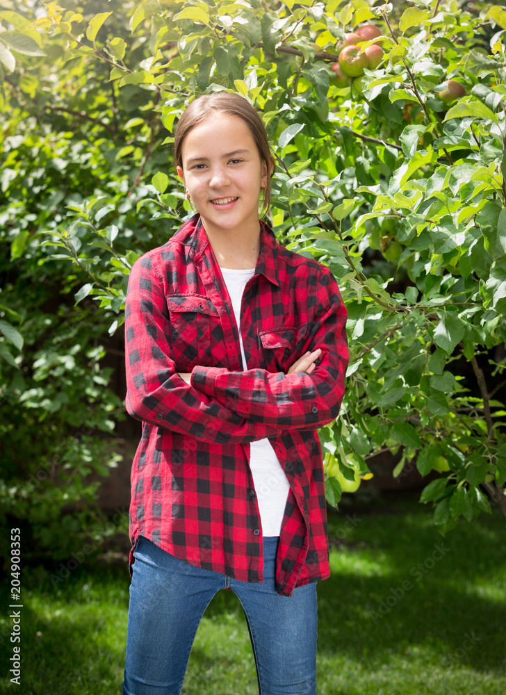 Portrait of smiling teenage girl posing in garden with apple trees Portrait of smiling teenage girl posing in garden with apple trees