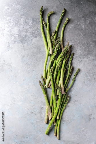 Raw uncooked organic green asparagus in row over grey texture background. Top view  copy space.