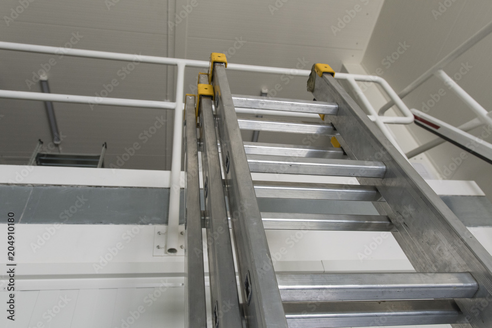 The top of the aluminum ladder leaning against the railing. The top of the aluminum ladder leaning against the railing.