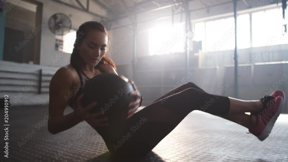 Shot of a fit young woman exercising with pilates ball at gym. Female athlete doing workout using medicine ball.
